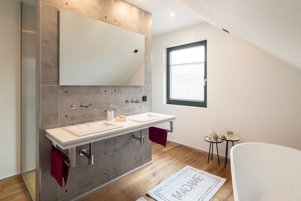 Modernes Badezimmer unter dem Dach mit großem Spiegel, Waschbereich und Holzfußboden.