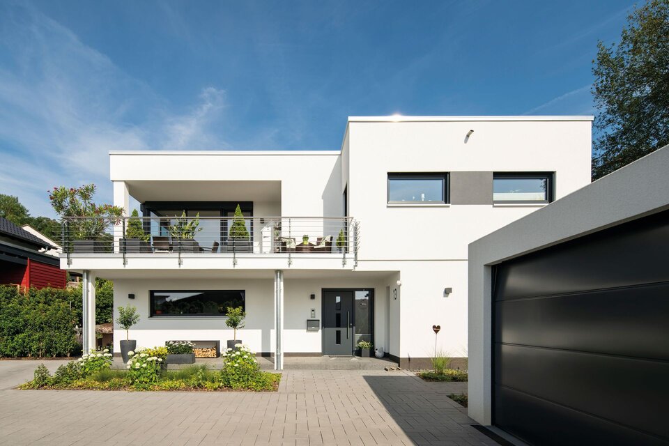Modernes FingerHaus im Bauhausstil mit Flachdach, großem Balkon, klaren Linien und angrenzender Garage, umgeben von gepflegtem Vorgarten.