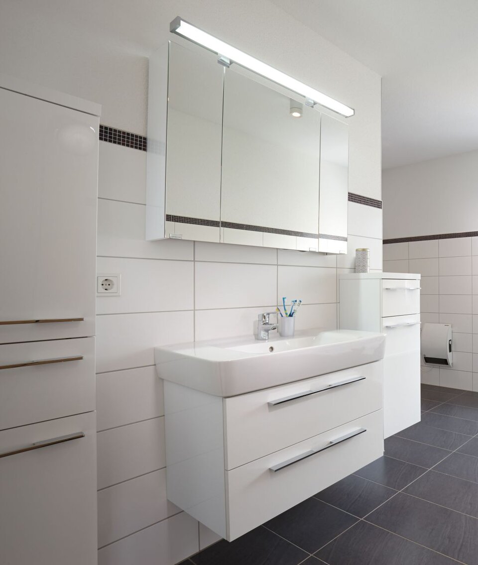 Helles Badezimmer mit großem Waschtisch, Einbauspiegel und Badewanne; moderne schwarz-weiße Fliesen.