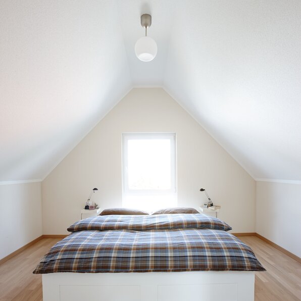Gemütliches Schlafzimmer im Dachgeschoss mit Doppelbett, Holzboden und schlichtem Design in einem frei geplanten FingerHaus.