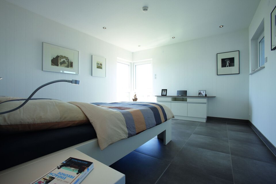 Gemütliches Schlafzimmer mit großem Bett und warmem Tageslicht.