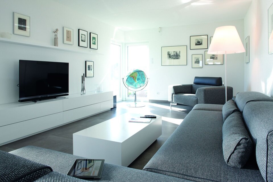 Helles Wohnzimmer mit großem Sofa, TV-Wand und modernen Details.