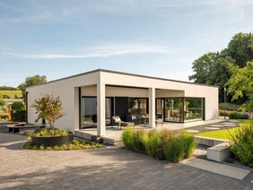 Musterhaus NIVO von FingerHaus in Frankenberg, ein moderner Bungalow mit Flachdach, weißer Fassade, großen Fensterflächen und überdachter Terrasse.