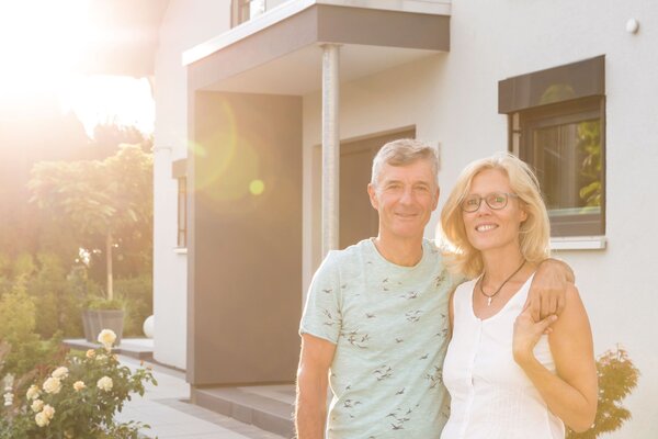 Zwei Personen stehen im sonnigen Eingangsbereich eines frei geplanten FingerHauses mit heller Fassade und großer Fensterfront.