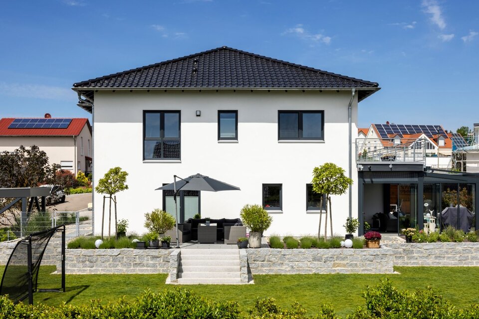 Modernes Einfamilienhaus von FingerHaus mit großem Garten, Terrasse und gepflegtem Außenbereich an einem sonnigen Tag.