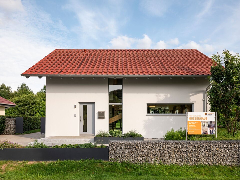Eingangsansicht des frei geplanten FingerHaus Musterhauses in Marburg mit rotem Satteldach, moderner Fassadengestaltung und gepflegtem Vorgarten.