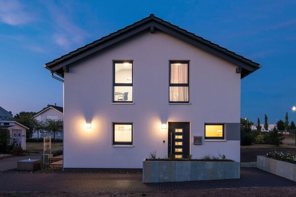 FingerHaus UNO 2.0 Musterhaus in Leipzig bei Abenddämmerung mit beleuchteter Fassade.