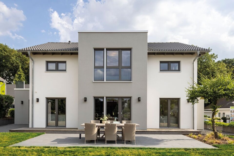 Außenansicht des FingerHaus-Musterhauses SENTO in Bad Vilbel mit moderner, symmetrischer Architektur, heller Putzfassade, großer Terrasse und gepflegtem Garten.