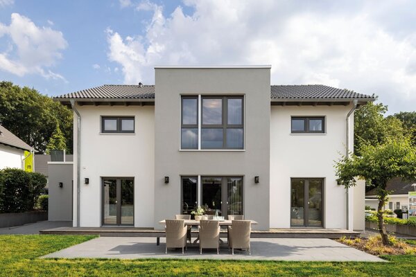 Außenansicht des FingerHaus-Musterhauses SENTO in Bad Vilbel mit moderner, symmetrischer Architektur, heller Putzfassade, großer Terrasse und gepflegtem Garten.