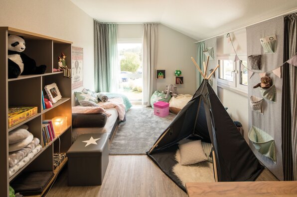 Kinderzimmer im FingerHaus SENTO 500 Musterhaus Frankenberg mit gemütlichem Bett, Spielteppich, Regal, Tipi-Zelt und freundlicher Einrichtung.