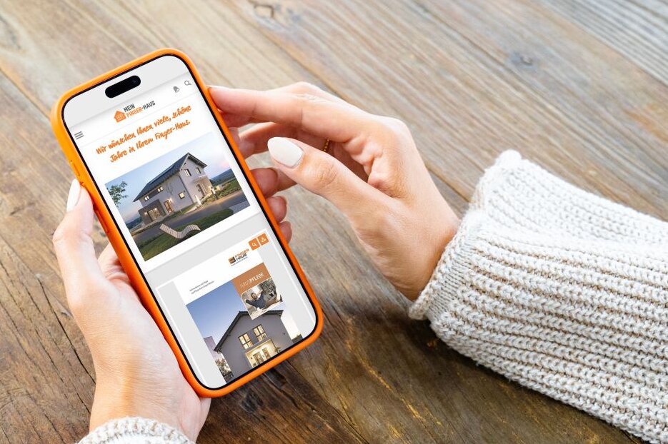 Person hält ein Smartphone mit dem FingerHaus Serviceportal in den Händen. Auf dem Display sind Inhalte und Tipps zur Hauspflege für Hausbesitzer zu sehen.