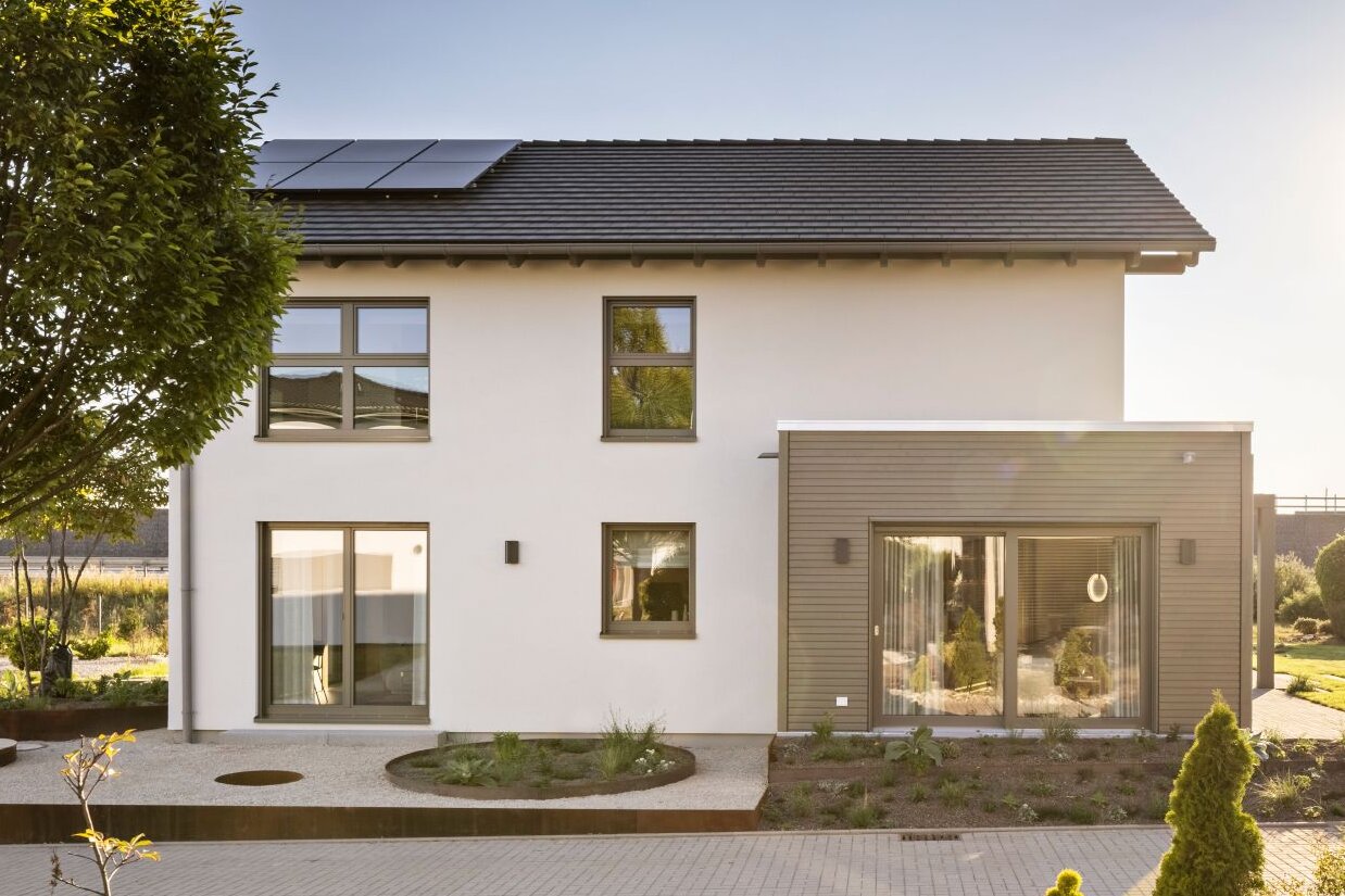 FingerHaus ARTIS 300 Musterhaus Nürnberg bei Sonnenuntergang mit moderner Fassade, Photovoltaikanlage und gepflegtem Vorgarten.