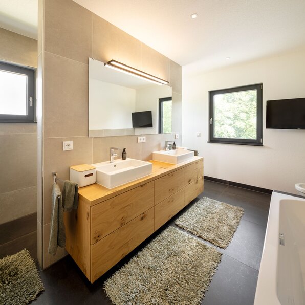 Modernes Badezimmer mit Doppelwaschtisch aus Holz, großen Spiegeln und zwei rechteckigen Waschbecken.