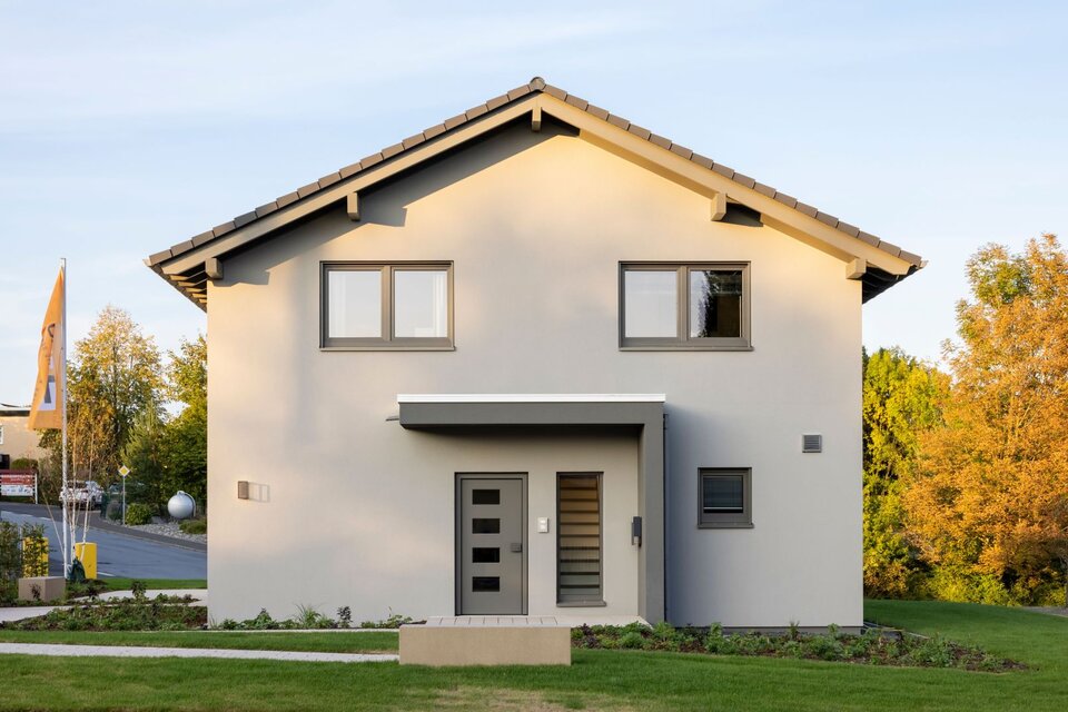 Frontansicht des FingerHaus ARTIS 300 Musterhauses Würzburg mit grauer Putzfassade, moderner Eingangstür und Satteldach.