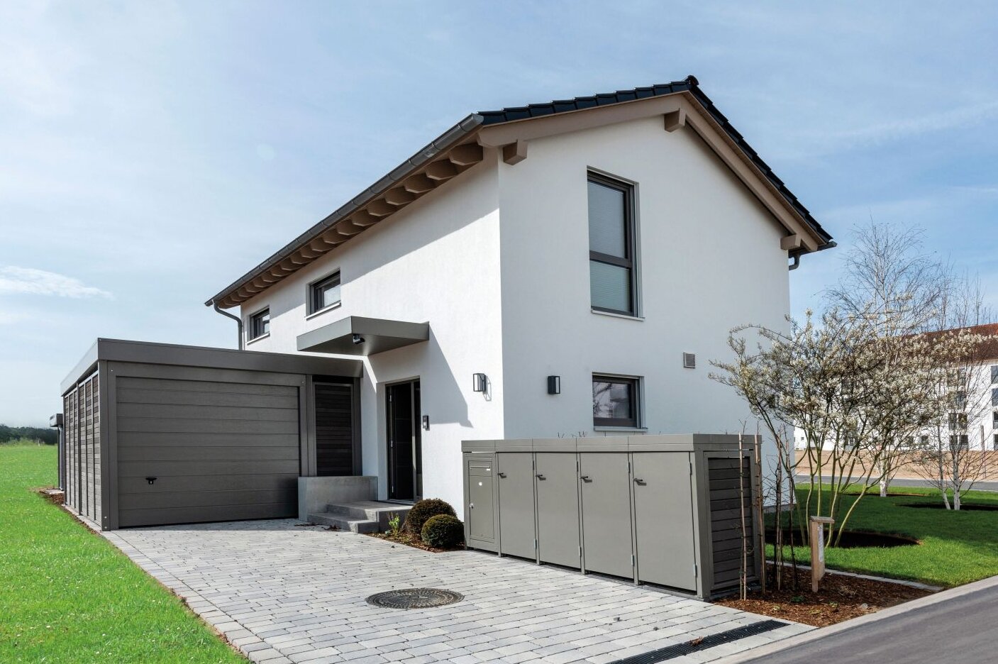 Musterhaus TALO von FingerHaus in Babenhausen mit angebauter Garage, gepflasterter Einfahrt und gepflegtem Vorgarten.