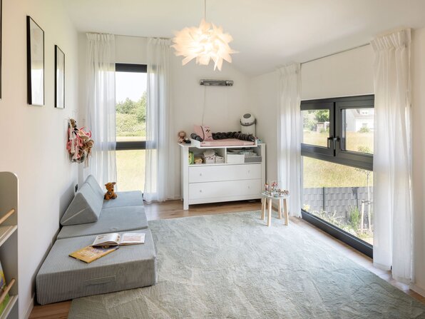 Helles Kinderzimmer mit Spielecke, Sofa, Wickelkommode und großen Fenstern