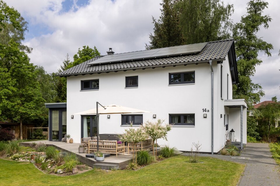 Frei geplantes FingerHaus mit moderner Fassade, großer Terrasse und gepflegtem Garten im Grünen.