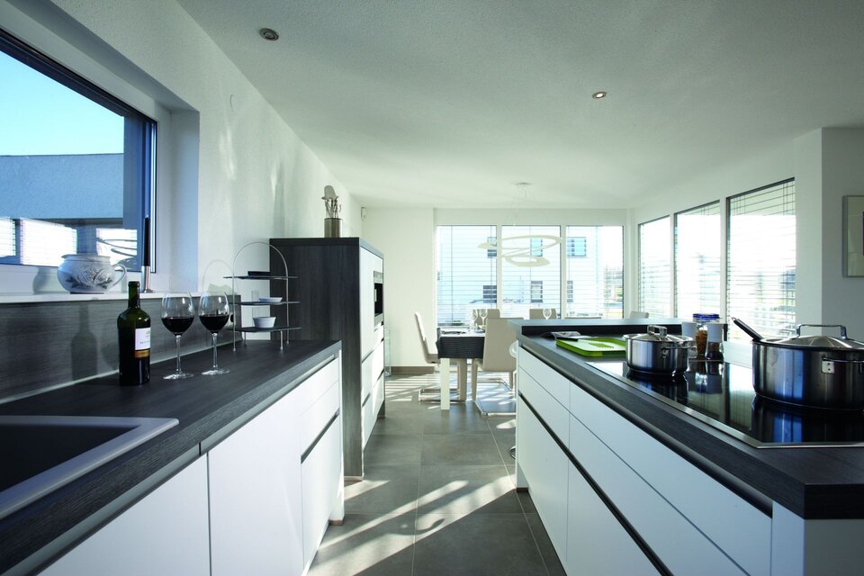 Moderne, helle Küche mit angrenzendem Essbereich und großen Fenstern.