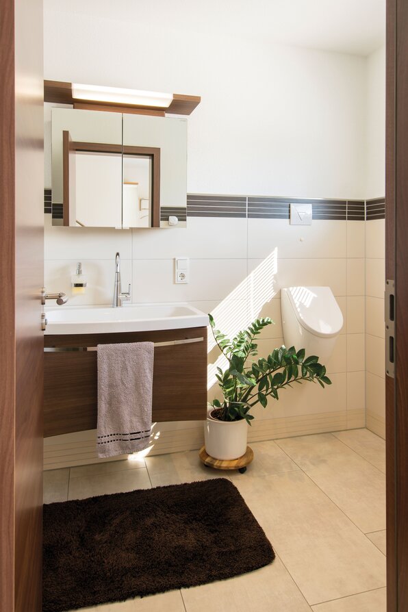 Modernes Gäste-Bad in einem frei geplanten Finger-Haus mit Wandwaschbecken, Spiegelschrank, stilvollen Fliesen, dekorativer Pflanze und Urinal.