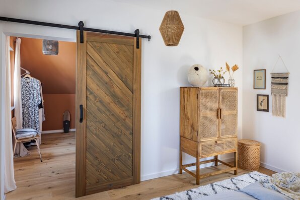 Frei geplantes Ankleidezimmer im FingerHaus mit Schiebetür aus Holz und natürlichem Interieur.