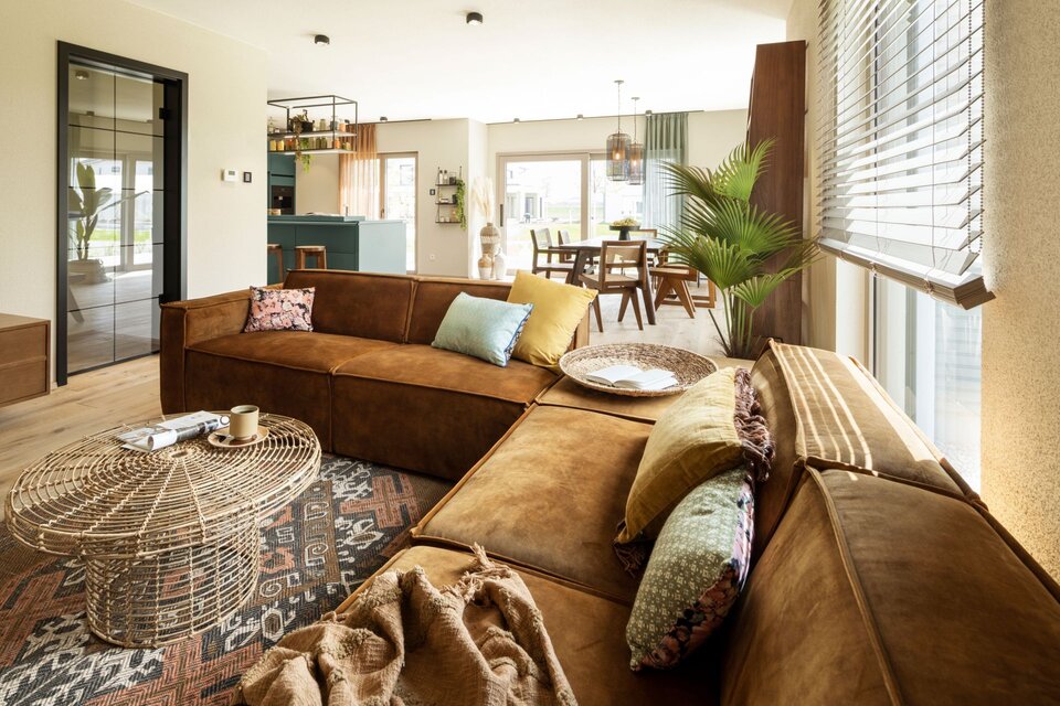 Wohnzimmer im FingerHaus ARTIS 400 Musterhaus Schwarzwald mit großem Ecksofa in Lederoptik, stilvollem Couchtisch, modernem Teppich und offener Raumgestaltung.