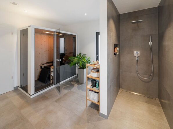 Modernes Badezimmer mit bodengleicher Dusche und geöffneter Infrarotkabine.