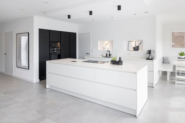 Moderne Küche in einem FingerHaus mit weißer Kochinsel, schwarzen Hochschränken und klaren Linien. Helles, minimalistisches Design mit viel Stauraum.