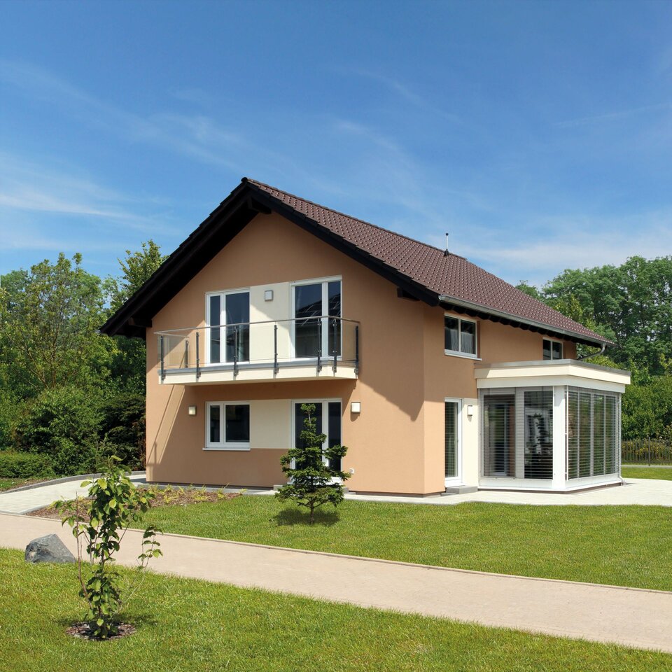 FingerHaus MEDLEY 310 – Musterhaus in Erfurt mit Satteldach, apricotfarbener Fassade und weißem Wintergartenanbau. Das Haus verfügt über einen Balkon mit Glasgeländer und einen gepflegten Garten mit Rasen und Gehweg