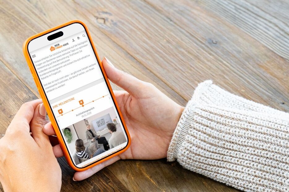Person hält ein Smartphone mit dem FingerHaus Serviceportal in den Händen. Auf dem Display sind Baufortschritt und Termine dargestellt.
