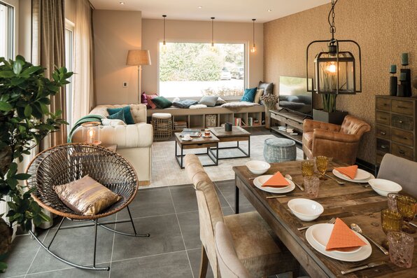 Wohn- und Essbereich im FingerHaus SENTO 500 Musterhaus Frankenberg mit rustikalem Esstisch, gemütlicher Sitzecke, großer Fensterbank und stilvoller Dekoration.