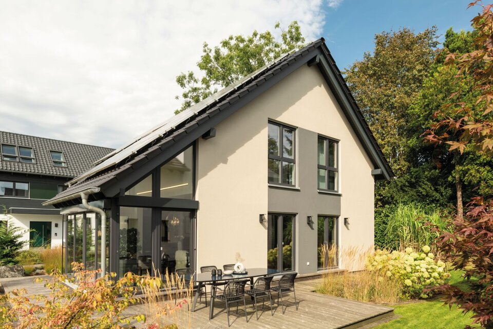 Modernes Fertighaus NEO in Wuppertal mit heller Fassade, Glaswintergarten, großzügiger Terrasse und Gartenbereich.