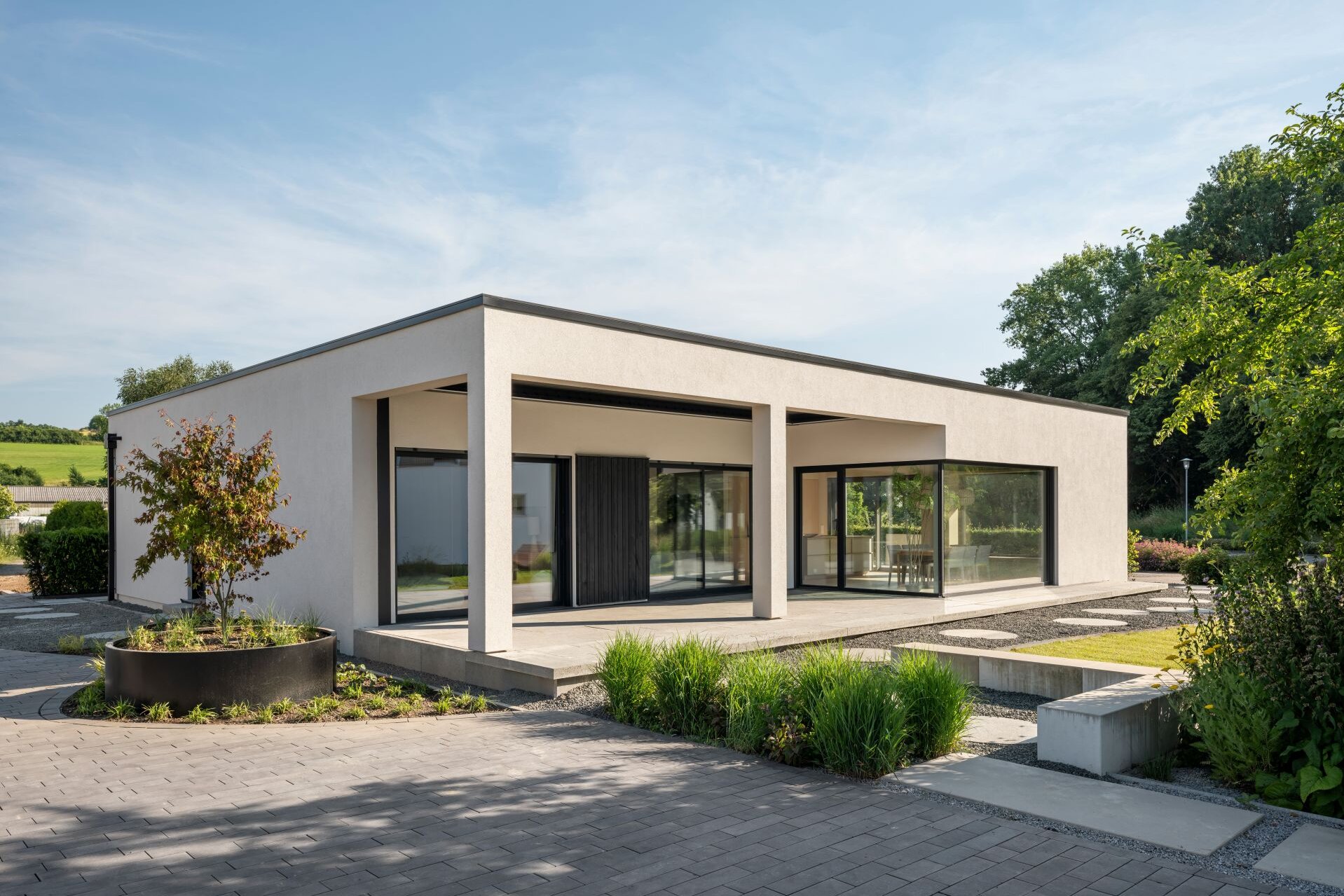 Musterhaus NIVO in Frankenberg mit moderner Bungalowarchitektur, weißer Putzfassade, überdachter Terrasse und großzügigen Eckfenstern.