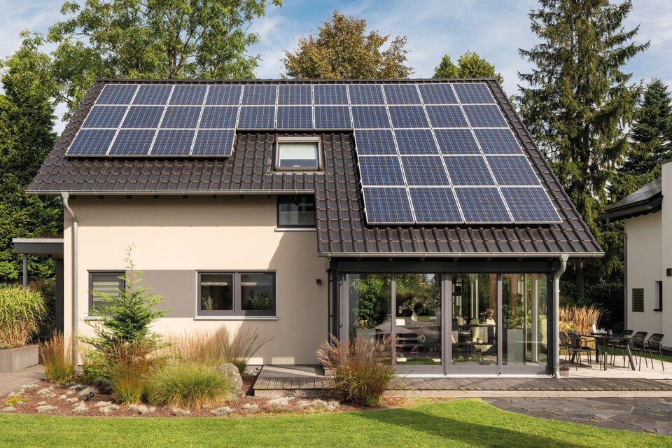 Musterhaus NEO in Wuppertal mit großzügiger Glasveranda, moderner Fassade und großflächiger Photovoltaikanlage auf dem Dach.