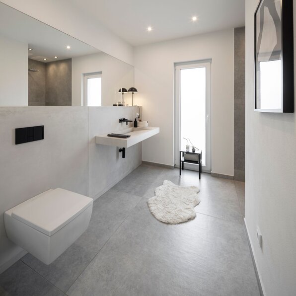 Modernes Badezimmer in minimalistischer Gestaltung mit Wand-WC, schwebendem Waschtisch und großem Spiegel.