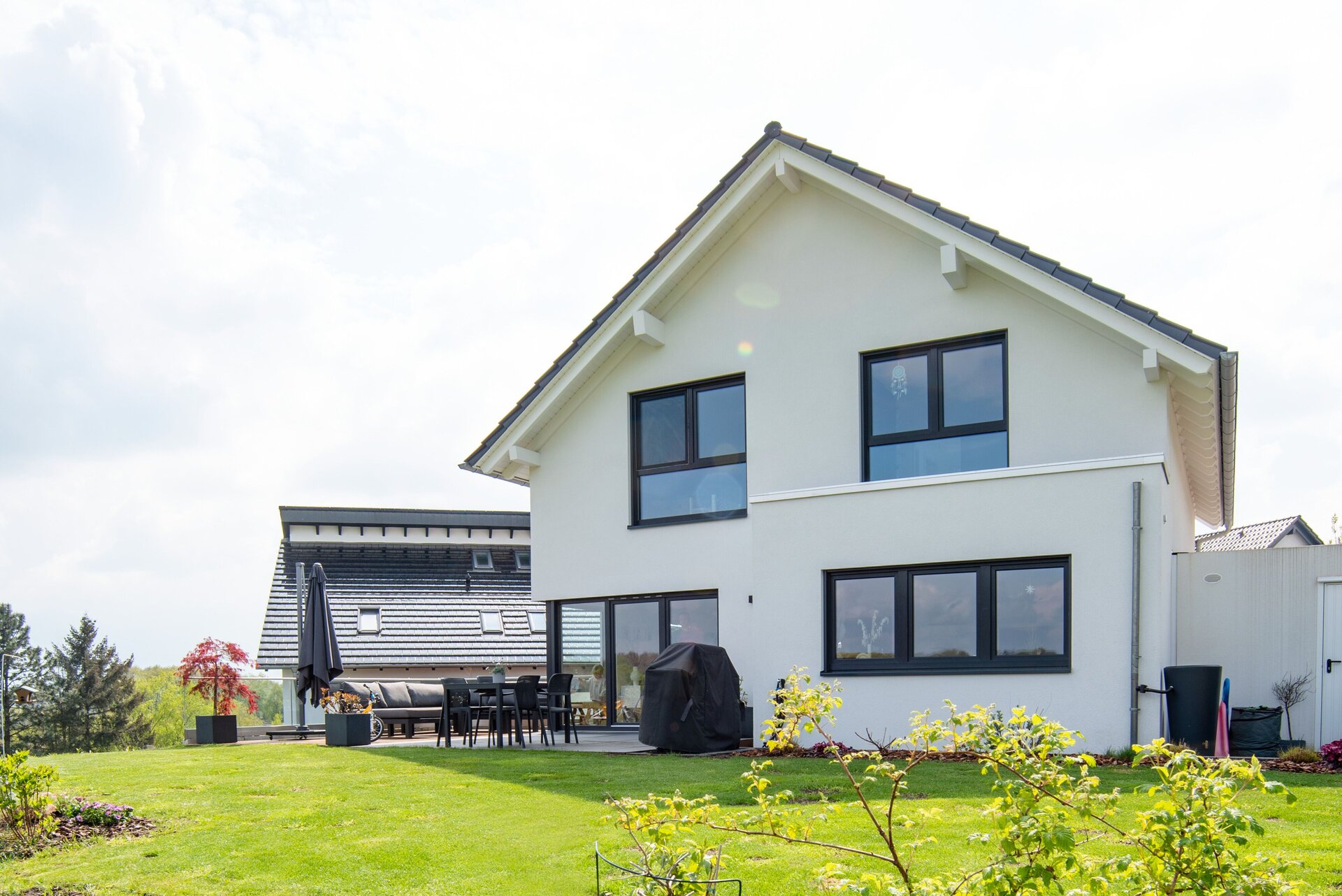 Rückansicht eines modernen frei geplanten FingerHaus mit großen Fenstern und Terrasse im weitläufigen Garten.