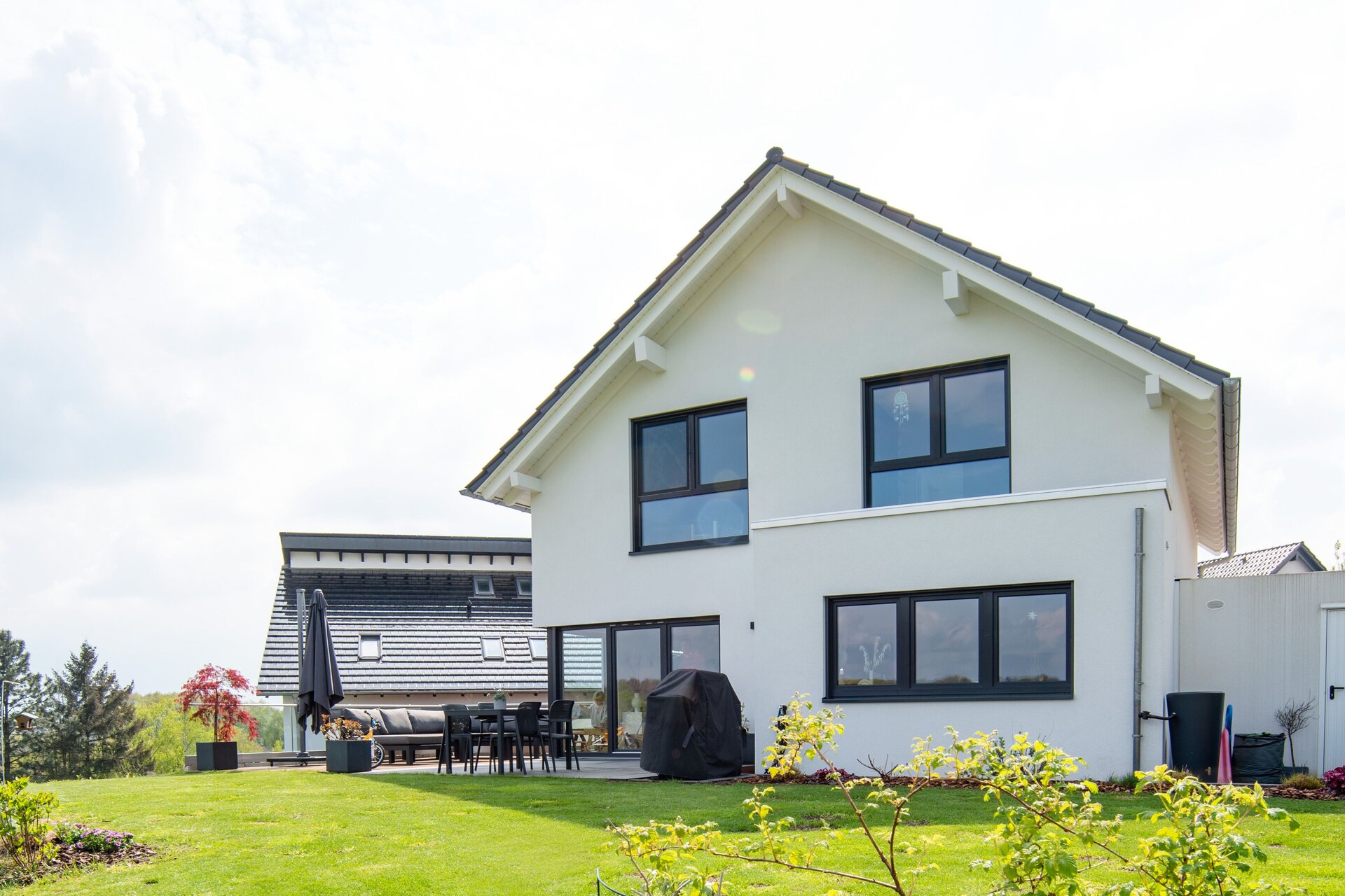 Rückansicht eines modernen frei geplanten FingerHaus mit großen Fenstern und Terrasse im weitläufigen Garten.