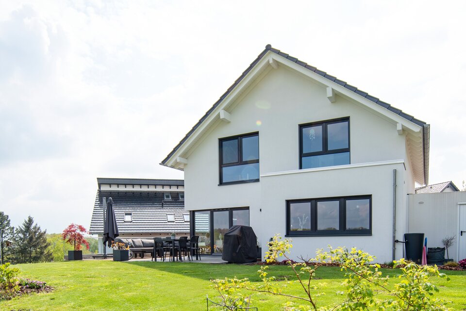 Rückansicht eines modernen frei geplanten FingerHaus mit großen Fenstern und Terrasse im weitläufigen Garten.
