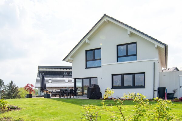 Rückansicht eines modernen frei geplanten FingerHaus mit großen Fenstern und Terrasse im weitläufigen Garten.