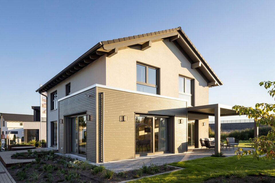 FingerHaus ARTIS 300 Musterhaus Nürnberg bei Abendsonne mit grauer Fassadenverkleidung, großem Balkonfenster und überdachter Terrasse.