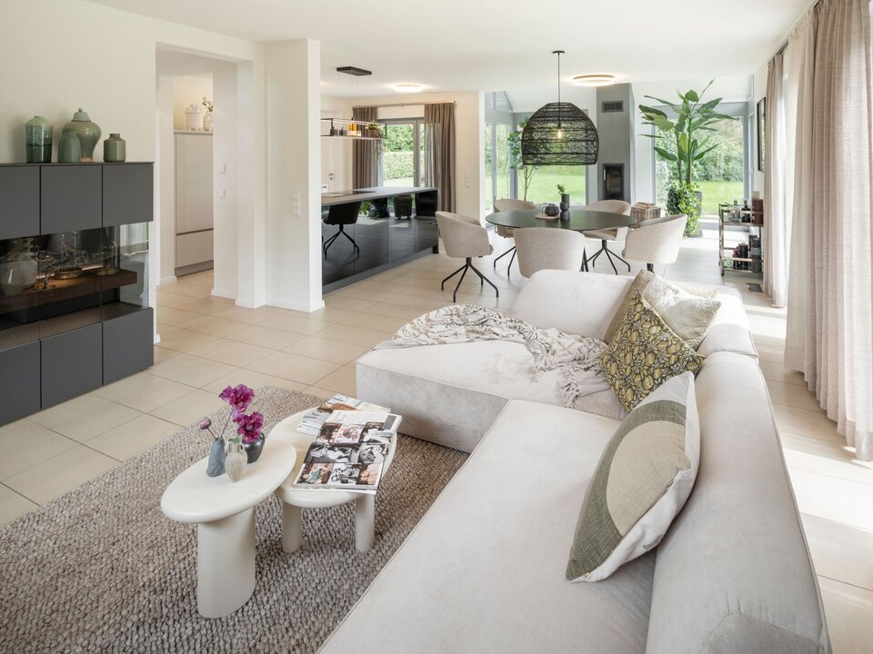 Großzügiger Wohn- und Essbereich im frei geplanten Musterhaus in Marburg mit gemütlicher Sofaecke, modernem Kamin und hellem Essplatz.