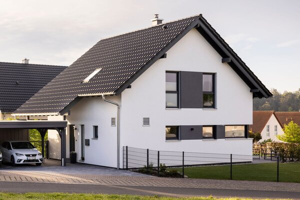 Modernes Einfamilienhaus mit Satteldach und Carport mit zwei parkenden Autos
