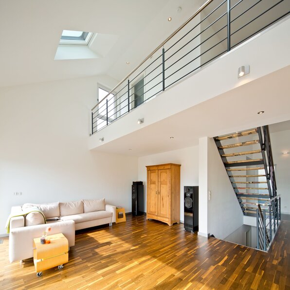 Offener Wohnbereich mit Galerie, freitragender Treppe, Metallgeländer und großer Fensterfläche in einem frei geplanten Finger-Haus.