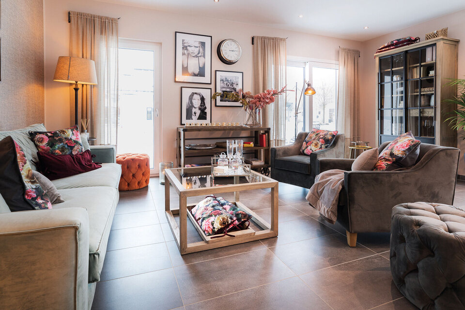 Gemütliches Wohnzimmer im Musterhaus MEDLEY 300 B in München/Poing mit eleganter Einrichtung, großen Fenstern und stilvoller Dekoration.