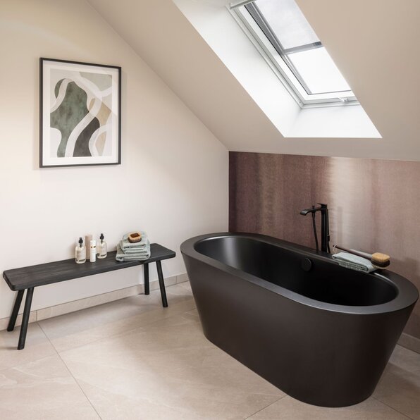 Modernes Badezimmer im Dachgeschoss des Musterhauses JUNO 300 in Mülheim-Kärlich mit freistehender schwarzer Badewanne unter Dachschräge.