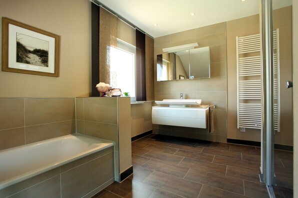 Modernes Badezimmer im MEDLEY 310, Musterhaus Erfurt, mit Badewanne, Dusche und großem Spiegel.