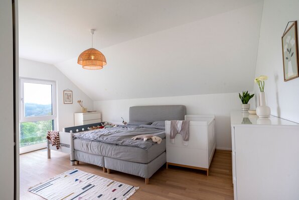 Schlafzimmer in einem frei geplanten FingerHaus mit Doppelbett, Kinderbett und moderner Einrichtung.