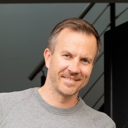 Familie mit zwei Erwachsenen und zwei Kindern steht vor dem Eingang eines modernen Hauses von FingerHaus Fertighaus.