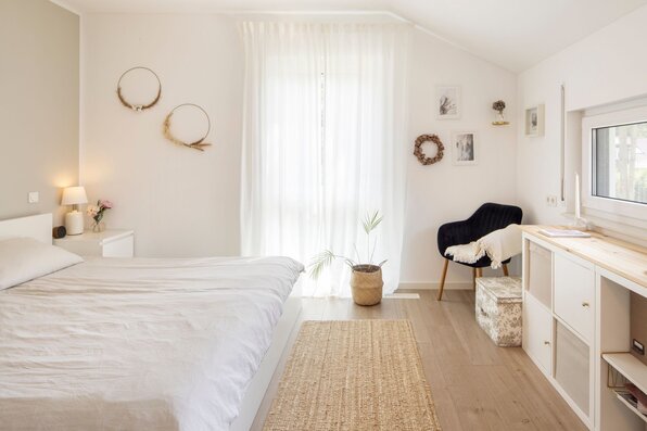 Helles Schlafzimmer im frei geplanten FingerHaus mit gemütlicher Einrichtung, Holzboden und schlichten Dekoelementen.
