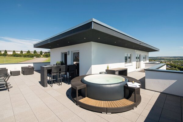 Große Dachterrasse eines modernen FingerHaus mit Whirlpool, Lounge-Bereich und weitem Blick über die Landschaft.