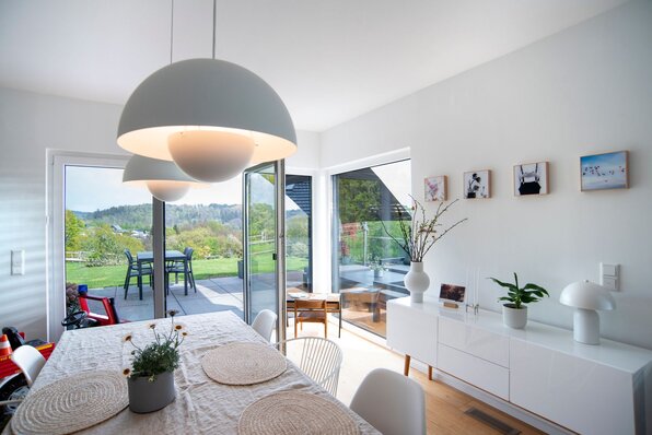 Esszimmer in einem frei geplanten FingerHaus mit großen Fenstern und Zugang zur Terrasse mit Blick ins Grüne.